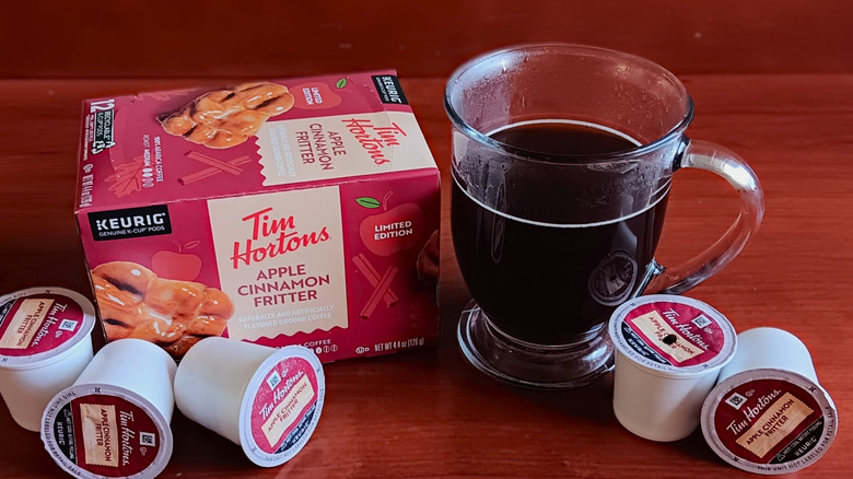Box of Tim Hortons Apple Cinnamon Fritter flavored coffee K-cups with mug of black coffee
