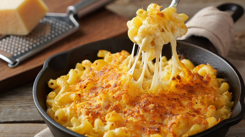 Baked mac and cheese spooned from a black skillet