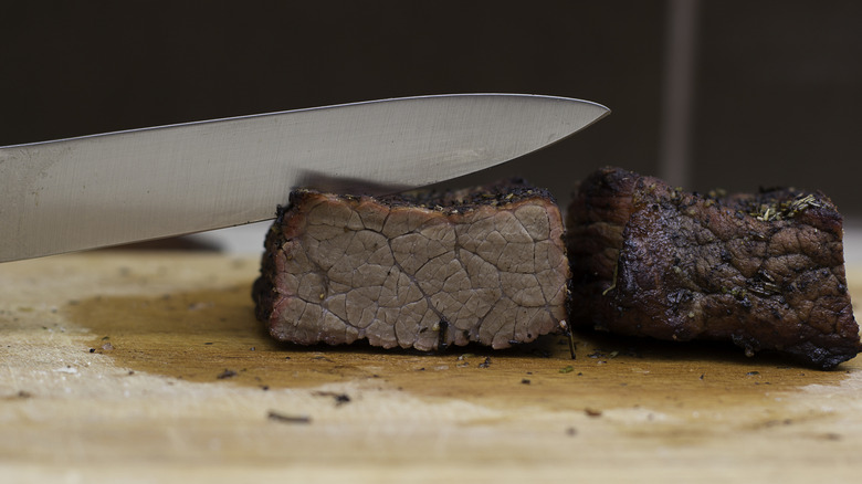 knife cutting overcooked steak