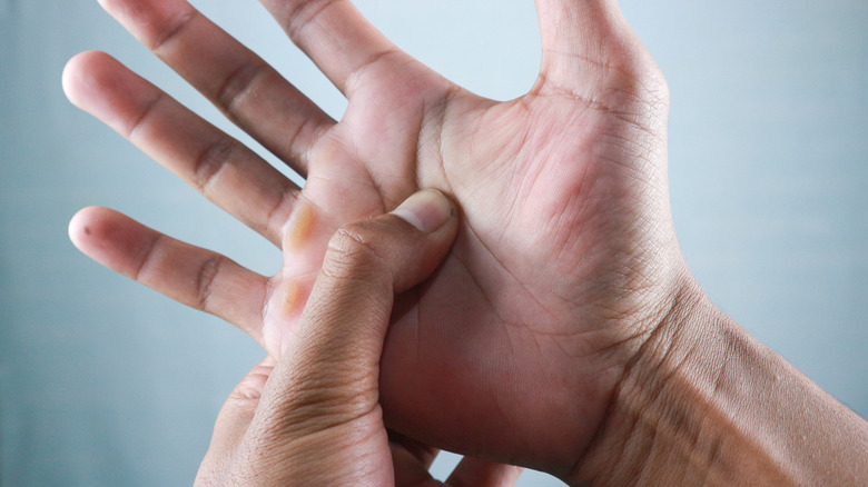 thumb pressing into open palm on gray background
