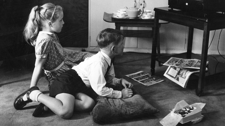 black and white image of children eating chocolates in front of the television