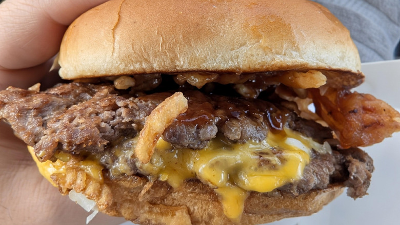 Close-up of someone holding a Steak 'n Shake Western Barbecue and Bacon Steakburger.
