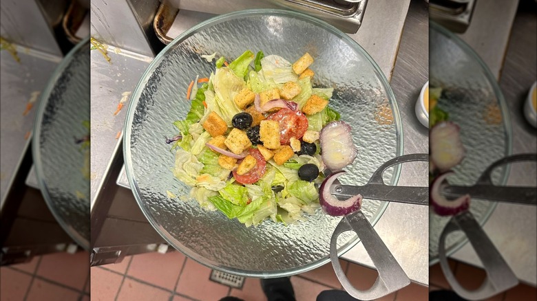 Mirrored image, top view of Olive Garden salad in glass bowl