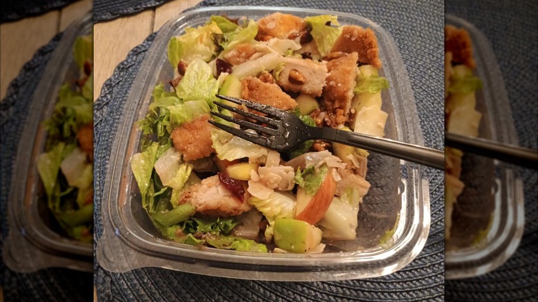 open salad with fork on round black place mat on table