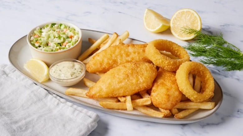 Platter of three fish fillets with fries, onion rings, coleslaw, tartar sauce, and lemons at Bob Evans