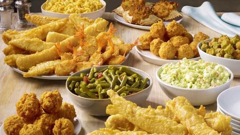 Assorted plates and dishes of fried fish and sides on table