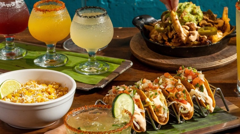 Assorted Tex-Mex dishes including tacos and nachos with margarita flight