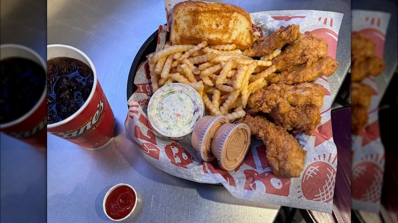A Raising Cane's combo meal on a metal counter, plastic cup of coleslaw front and center.