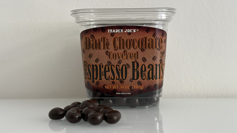 Dark chocolate covered espresso beans in front of plastic container