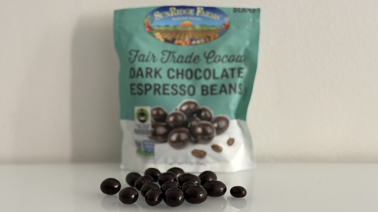 Darkk chocolate covered espresso beans on table in front of pouch