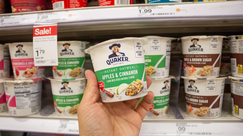 Person taking apple and cinnamon instant oatmeal cup from grocery store shelf