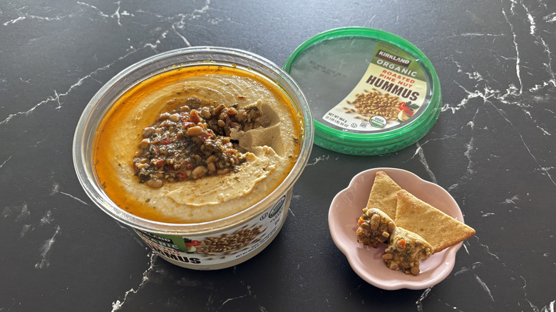 Costco hummus container next to sample and pita chips in small bowl
