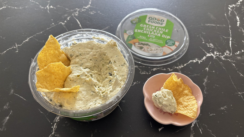 Costco chicken enchilada dip container with tortilla chips next to chip and dip sample in small bowl