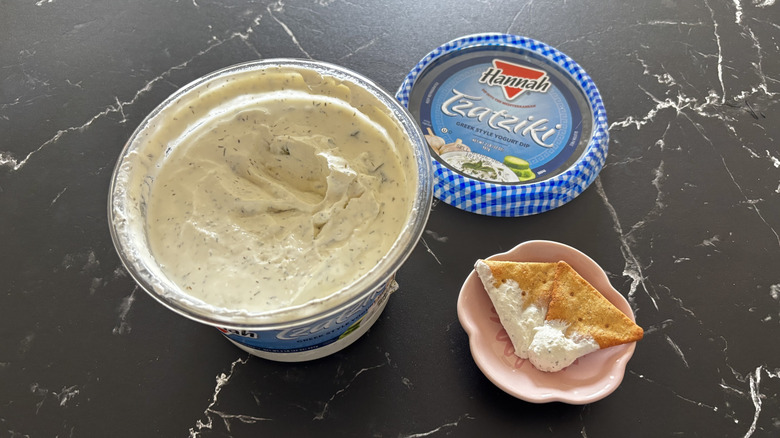 Costco tzatziki dip container next to pita chips with dip on small plate