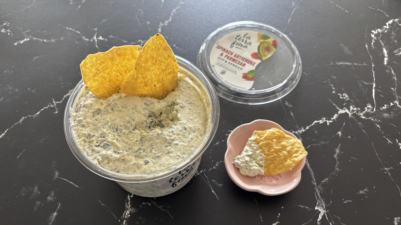 Costco spinach artichoke dip container with chips and sample on small plate