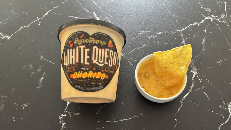 Costco white queso with chorizo container next to chip and dip sample in small bowl