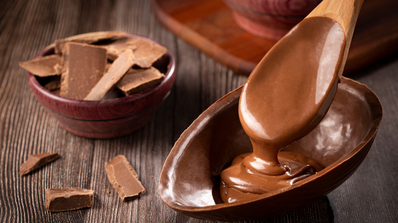 spoon drizzling chocolate into chocolate egg shell