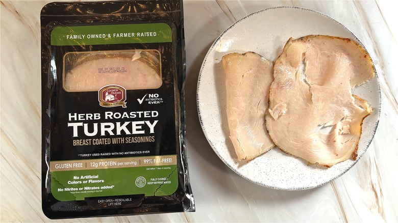 Slices of Cooper Farms oven-roasted turkey on white plate next to package on table