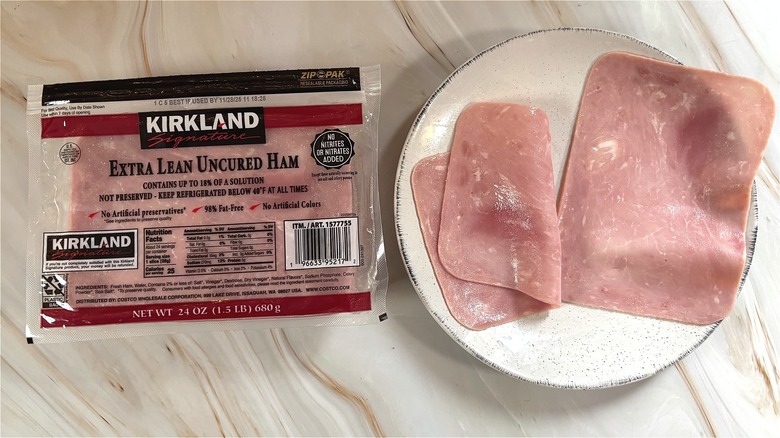 Slices of Kirkland extra lean uncured ham on white plate next to package on table