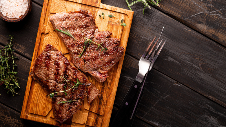 steak on a wooden cutting board with thyme sprigs