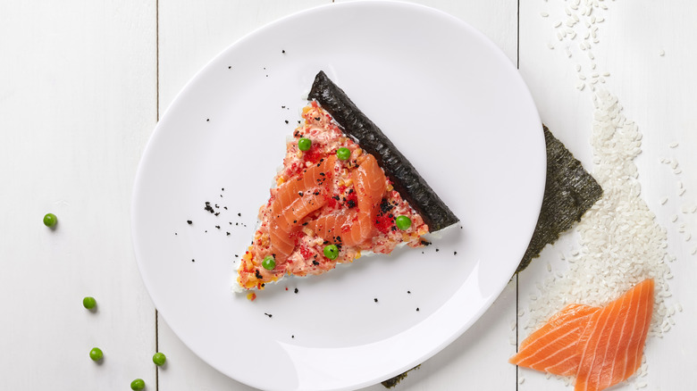 Sushi pizza with salmon and a nori crust, on a white plate