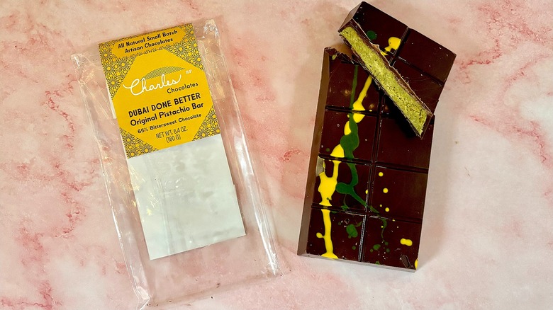 Charles Chocolates Dubai chocolate package next to bar on pink marble surface