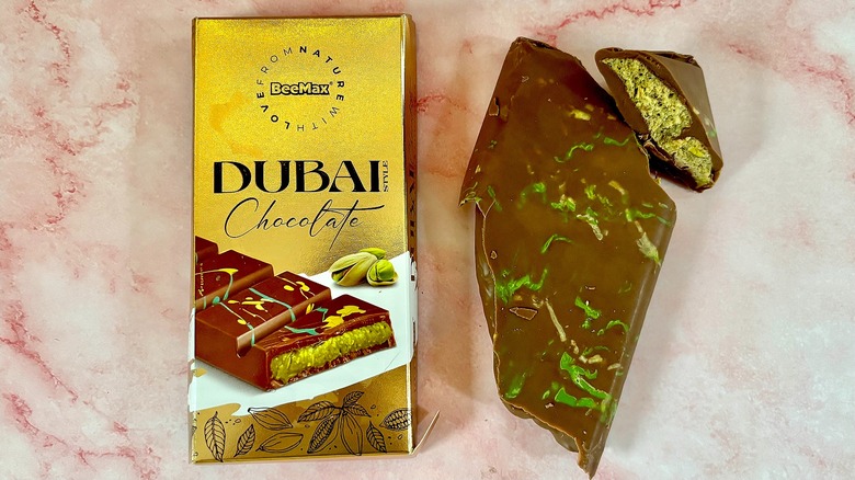 BeeMax Dubai chocolate package next to bar on pink marble surface