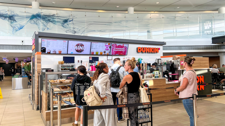 Dunkin' restaurant storefront with line of customers at Chicago O'Hare International Airport