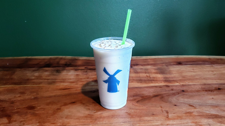 Dutch Bros vanilla milkshake on wooden table.