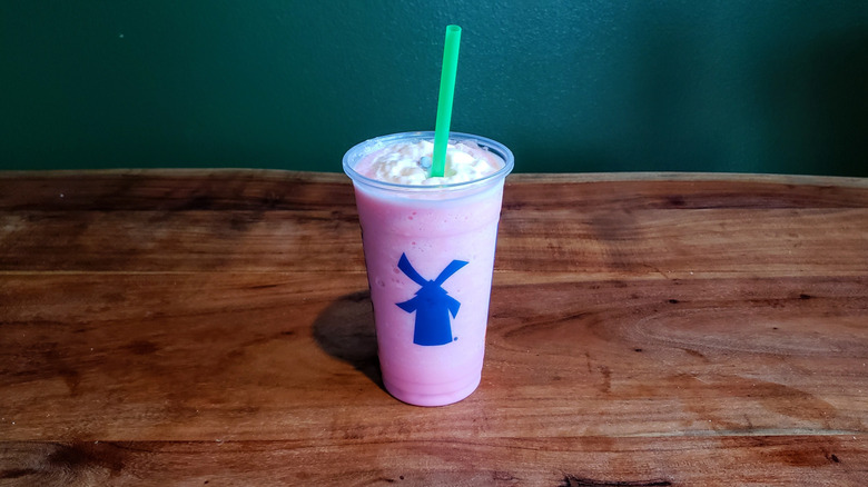 Dutch Bros strawberry shake on a wooden table.