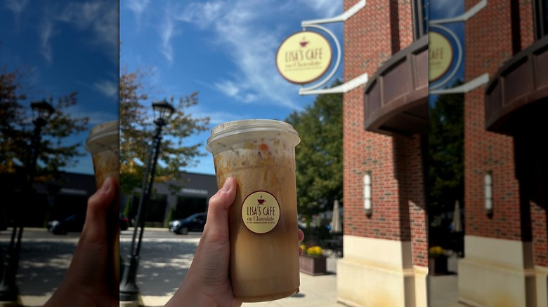 Hand holding drink outside of Lisa's Cafe on Chocolate, sign in background
