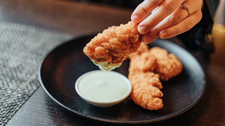 Person dipping chicken into ranch dressing