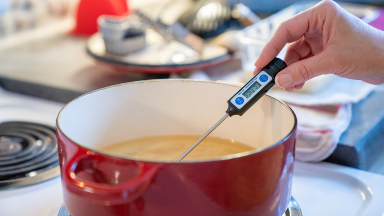 a dutch oven with oil and a thermometer checking the temperature