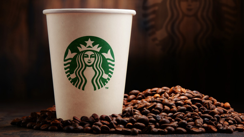 A Starbucks cup on a pile of coffee beans.