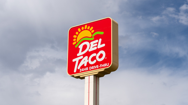 Red Del Taco sign against cloudy sky background
