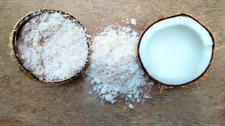 Two half shells of coconut, one filled with desiccated coconut