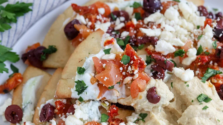 Mediterranean nachos with olives on white plate