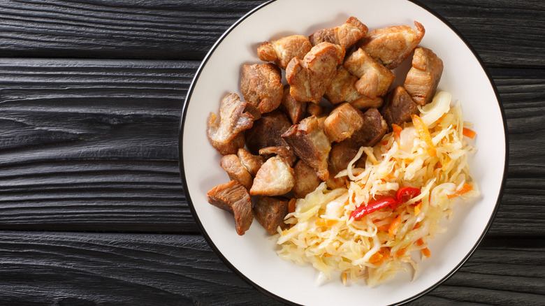 A white bowl filled with traditional Haitian griot with meat and slaw
