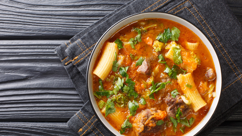 A top view image of a bowl of Haitian soup with beef and noodles in it