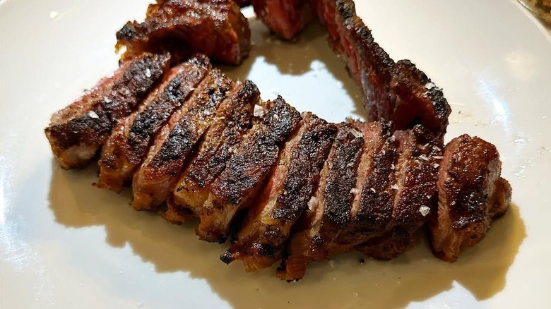 Sliced strip steak on white plate