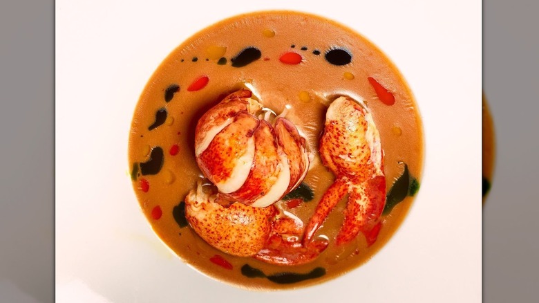 Lobster newberg in white bowl with leaves on blue table
