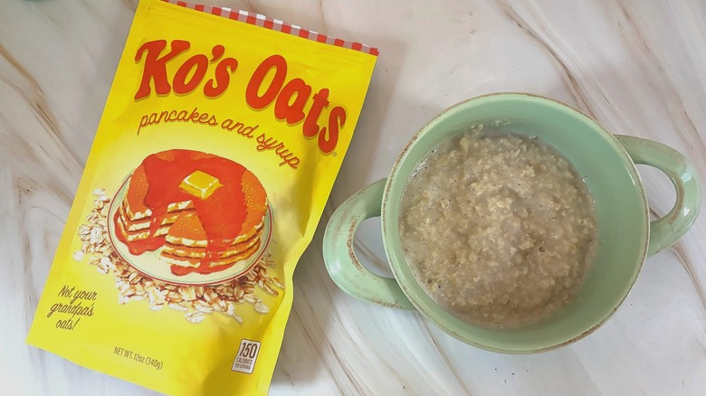 Ko's Oats Pancakes and Syrup bag next to blue bowl of oats on marbled surface