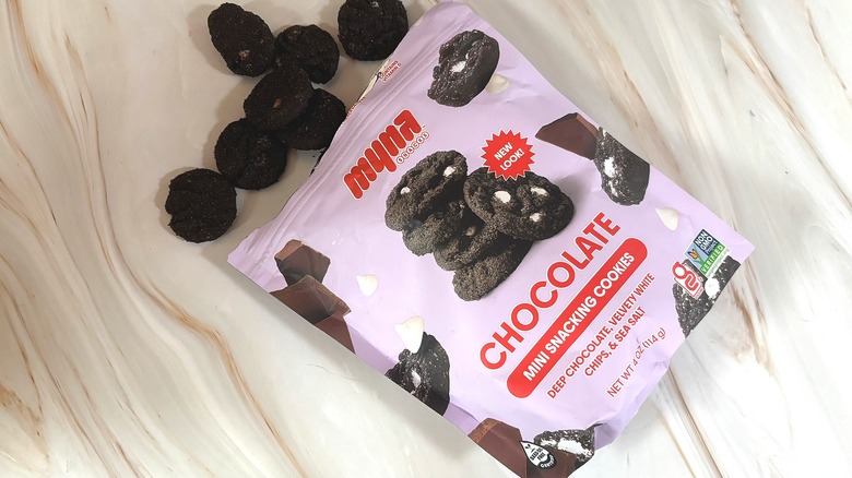 Cookies spilling out of purple bag of Myna snacking cookies on marbled surface