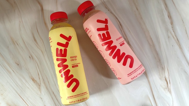 Unwell Hydration mango citrus and strawberry bottles on marbled surface