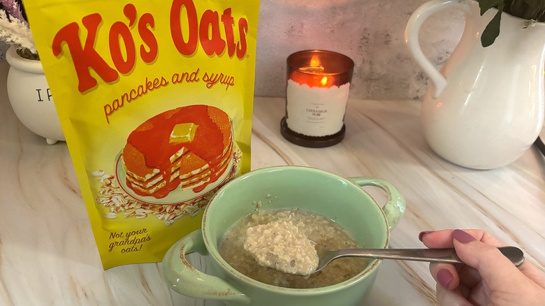 Ko's Oats in blue bowl in front of package, candle and pitcher behind