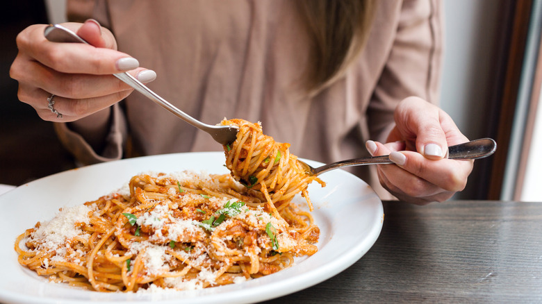 close up of woman twirling spaghetti around fork