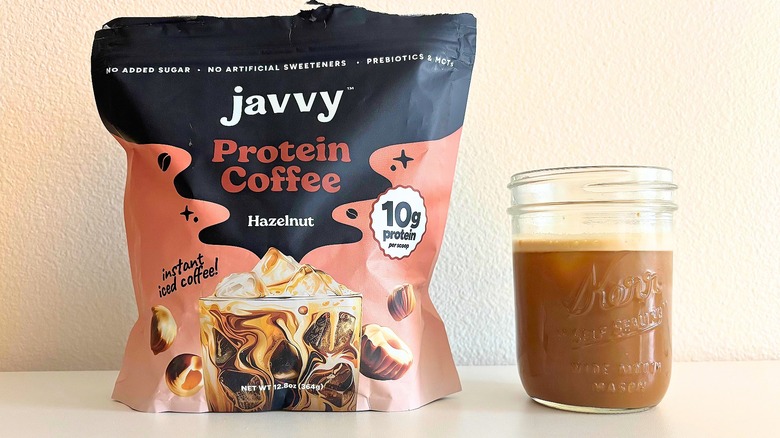 Bag of Javvy hazelnut coffee mix next to kerr jar of coffee on white table