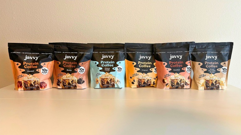 Six bags of Javvy protein coffee mixes on white table