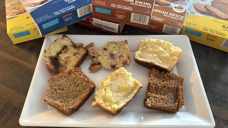 Krusteaz pound cake and quick bread mix boxes and slices on white platter on wooden table.