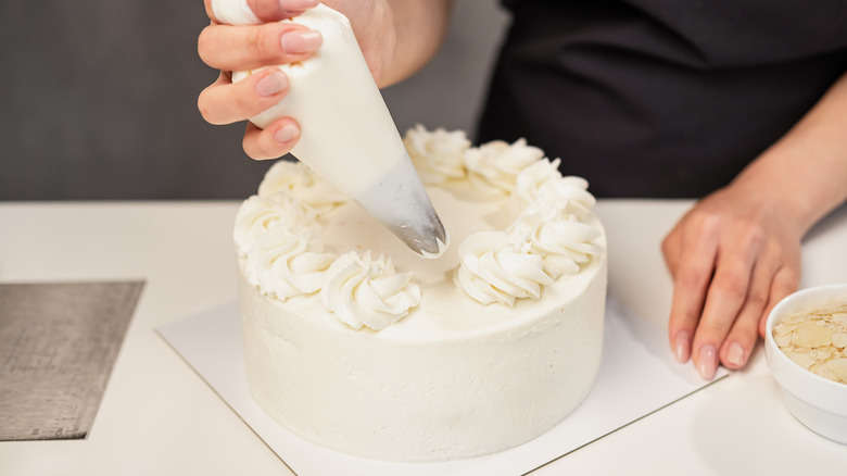 Pastry chef decorating a white cake